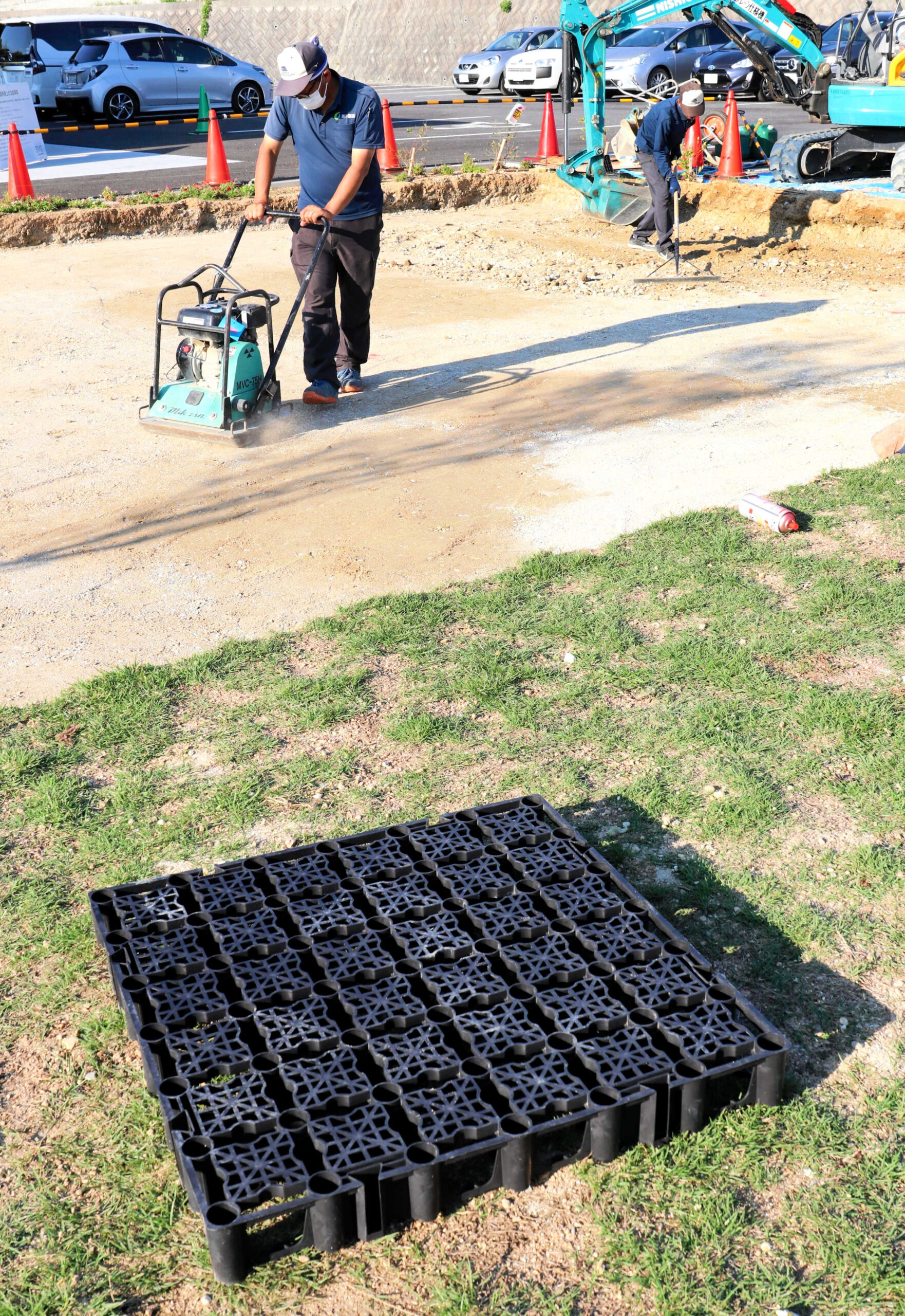 雨水をためるパレット（手前）を敷き詰めるため天然芝広場を掘削する阪神園芸の職人ら＝いずれも神戸市西区平野町のバサラヴィレッジグリーン
